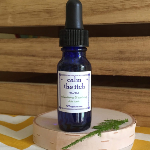 512organics bottle of Calm the Itch essential oils blend 1/2 oz with wood background